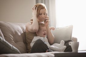 Woman frustrated on the phone while holding baby