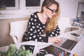 A photo of a woman at a laptop computer writing a cover letter.