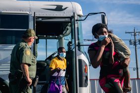 Migrants exit a Border Patrol bus and prepare to be received by the Val Verde Humanitarian Coalition after crossing the Rio Grande on September 22, 2021 in Del Rio, Texas. Thousands of immigrants, mostly from Haiti, seeking asylum have crossed the Rio Grande into the United States. Families are living in makeshift tents under the international bridge while waiting to be processed into the system. U.S. immigration authorities have been deporting planeloads of migrants directly to Haiti while others have crossed the Rio Grande back into Mexico.