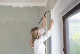 A person paints a wall in a house.