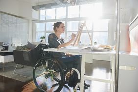 woman in wheelchair painting on easel