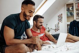 Gay couple at home using internet and laptop to buy online