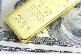 Gold bar laying on top of U.S. Currency