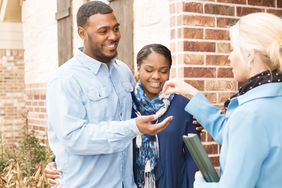 young adult couple receives a house key to their first home from their realtor. 