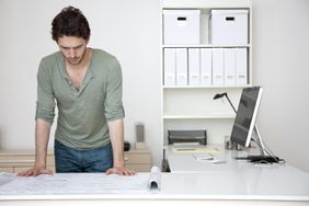 Caucasian man looking at blueprints in office