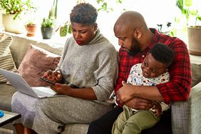 Couple with young son seated on couch with laptop and mobile