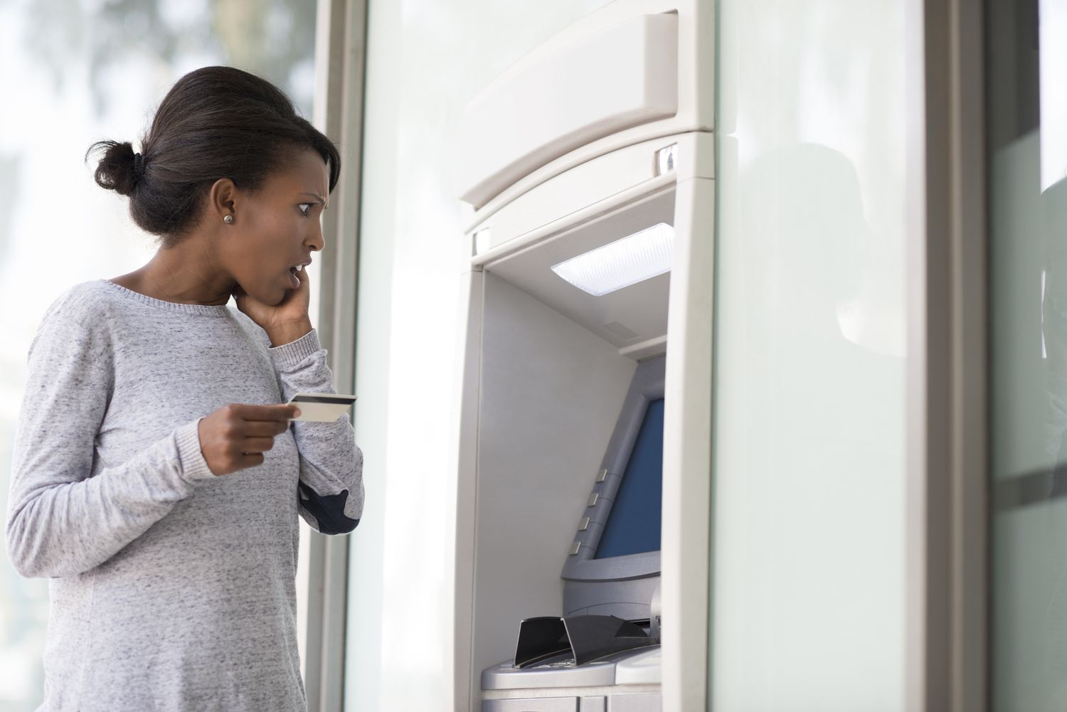 A young woman with a shocked facial expression looking at the ATM
