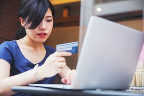 Woman holding a credit card and working on a laptop