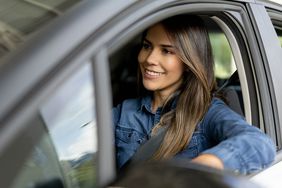 Smiling young woman behind the wheel of a car.