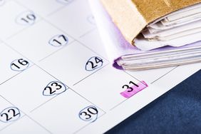 Close-up of file folders and calendar with dates circled and highlighted