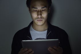 A person holding up a tablet and staring intently at the screen