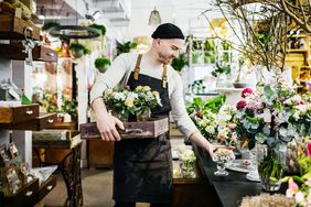  A flower shop owner or employee makes adjustments to an arrangement.