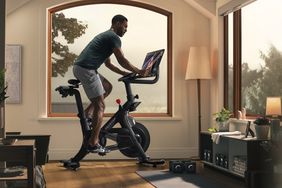 A Black man works out on a Peloton stationary bicycle.