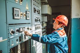 Senior woman, engineer-technician, is operating complex equipment on electrical dispatching station, checking system status, and adjusting parameters of the power grid.