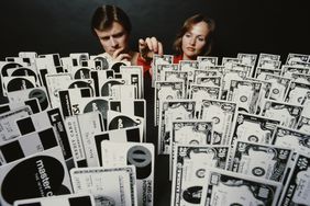 A man and a woman choose from an array of credit cards and dollar banknotes, 1979.