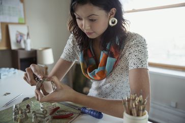 Woman sitting at her desk making jewelry