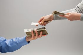 Close-up of man's hands counting a stack of money into another man's hand