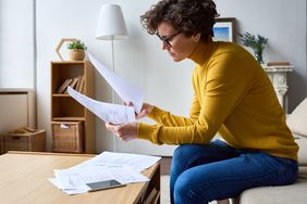 Woman on living room sofa reviews paper tax forms