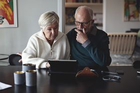 Senior couple using a digital tablet while sitting at a table in the living room