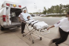 Blurred shot of emergency medical technicians wheeling a gurney with a patient on it away from ambulance