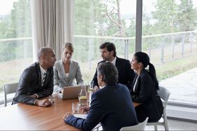 Male and female businesspersons gathered around a conference table