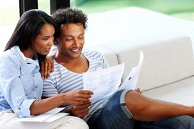 Young couple reading financial and tax paperwork at home.