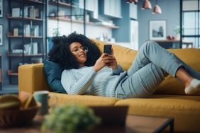 A person lounges on a couch looking at a phone.