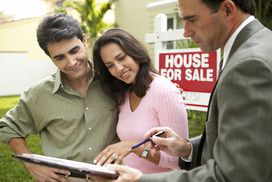 A couple talking to a real estate agent with a tablet outside a house for sale