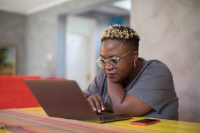Black woman looking closely at laptop.