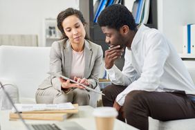 A man and a woman review the prequalification terms of a loan in a modern office