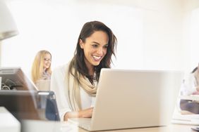 Smiling woman using laptop in office