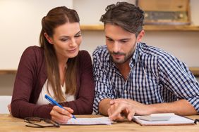 Young couple crunches numbers with pen, papers, and calculator