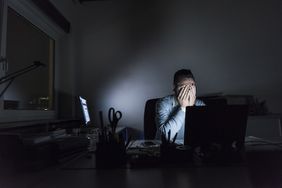 Exhausted businessman sitting at desk in office at night
