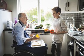 Disabled retiree preparing food with grandson in kitchen