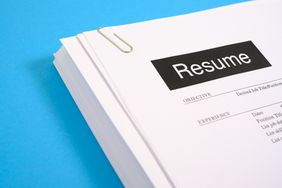 A stack of resumes on a blue desk.