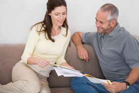 Couple sitting on a sofa looking at paperwork