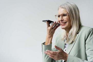 Businesswoman talking on speaker phone with her virtual personal assistant