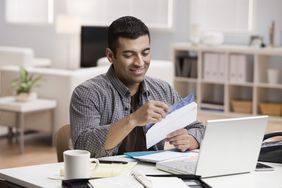 Smiling man opening mail in home office 