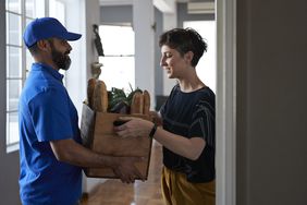 Delivery worker handing off a grocery bag to a client