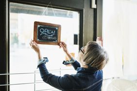 Woman hanging "Open" sign in her shop window