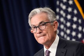 Federal Reserve Chairman Jerome Powell stands at a podium and listens to a question from the audience.