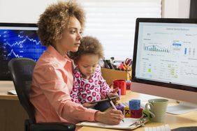 Woman with child in her lap comparing charts on computer