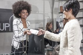 Store employee handing customer a bag and shopping receipt