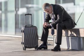 Businessman with graying hair waits with his luggage.r