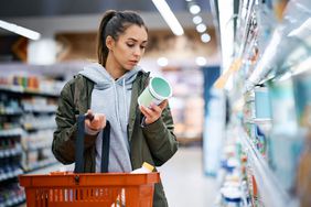 Young woman reading label on a product in supermarket