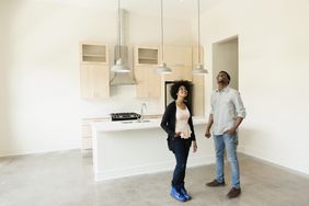Smiling couple standing in the vacant kitchen of their first home