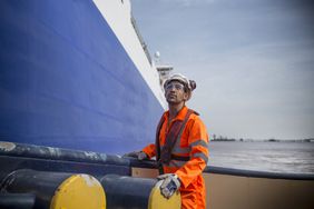 Tug worker looking ahead as he guides a cargo ship in port