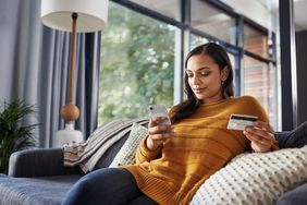 Person seated on sofa with a phone and a credit card