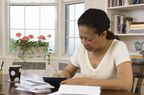 Mature woman writing check in home office