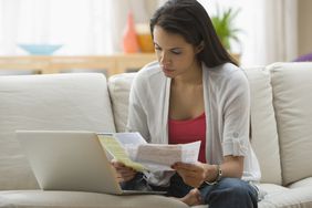 Hispanic woman paying bills online with laptop